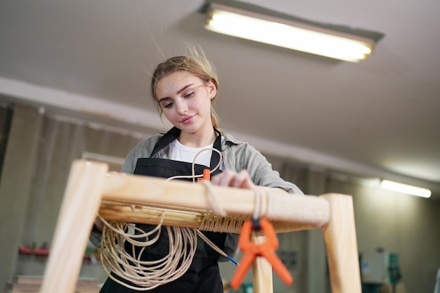 Mujer hermosa joven trabajando en la sala de taller de bricolaje de carpintero. Propietaria de una pequeña empresa, mujer joven que trabaja en una fábrica de muebles.