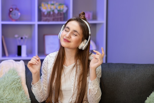 Mujer hermosa joven en traje brillante disfrutando de la música en casa.