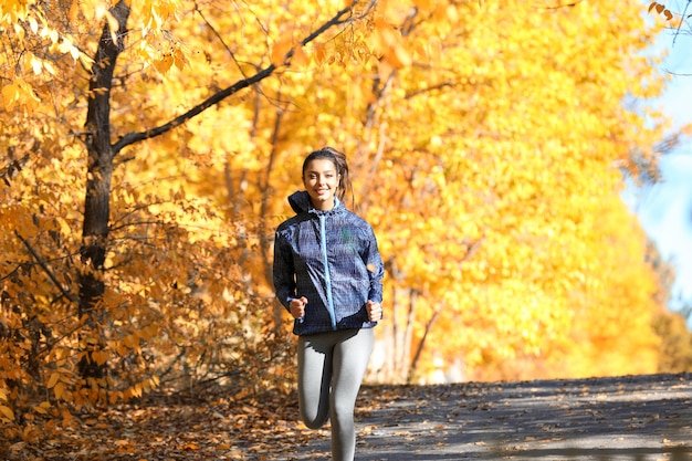 Mujer hermosa joven trotar en el parque otoño