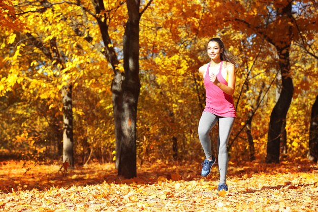 Mujer hermosa joven trotar en el parque otoño