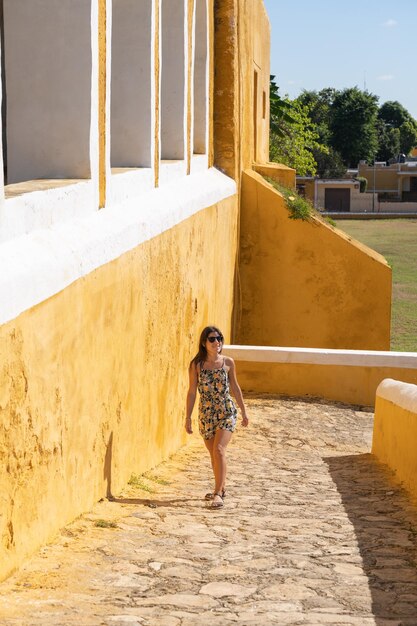 Foto mujer hermosa joven turista caminando por la entrada del convento de san antonio en izamal méxico