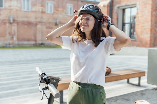 Mujer hermosa joven usa casco de bicicleta para andar en bicicleta excepto un scooter eléctrico