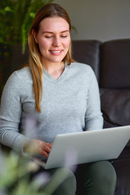 Mujer hermosa joven usando una computadora portátil en casa