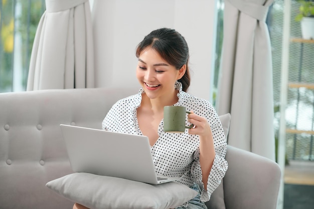 Mujer hermosa joven usando una computadora portátil en casa