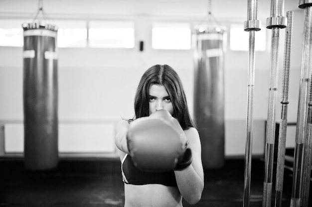 Mujer hermosa joven, usar guantes de boxeo haciendo ejercicios y trabajando duro en el gimnasio