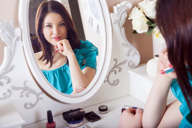 Mujer hermosa joven con vestido aplicar maquillaje