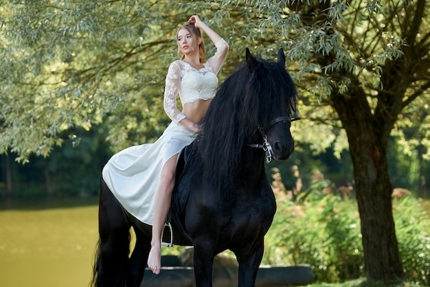 Mujer hermosa joven con un vestido blanco montando a caballo