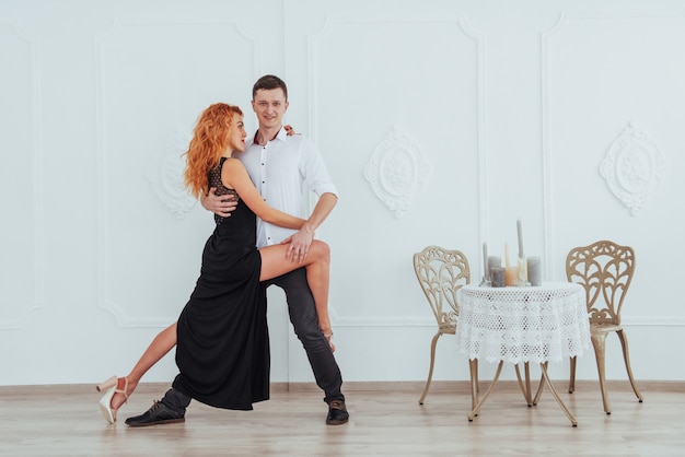 Mujer hermosa joven en un vestido negro y un hombre en camisa blanca bailando.