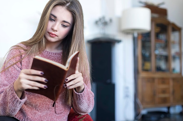 Mujer hermosa leyendo un libro en casa.