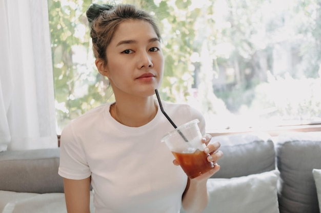 Una mujer hermosa y linda bebiendo café helado en el café.