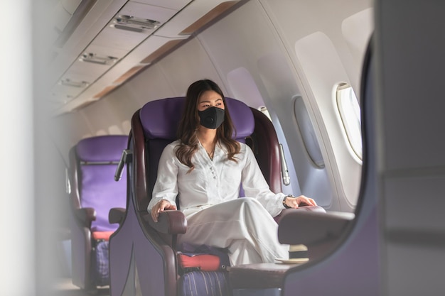 Mujer hermosa con máscara sentada en un avión corporativo