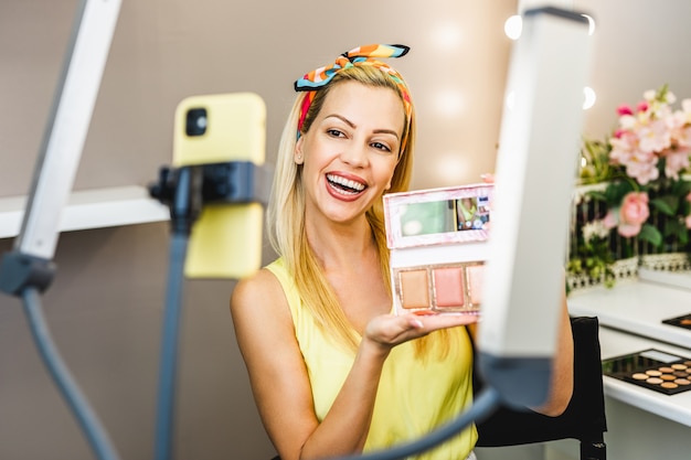 Mujer hermosa de mediana edad y belleza profesional maquilladora vlogger o blogger grabando un tutorial de maquillaje para compartir en el sitio web o las redes sociales.