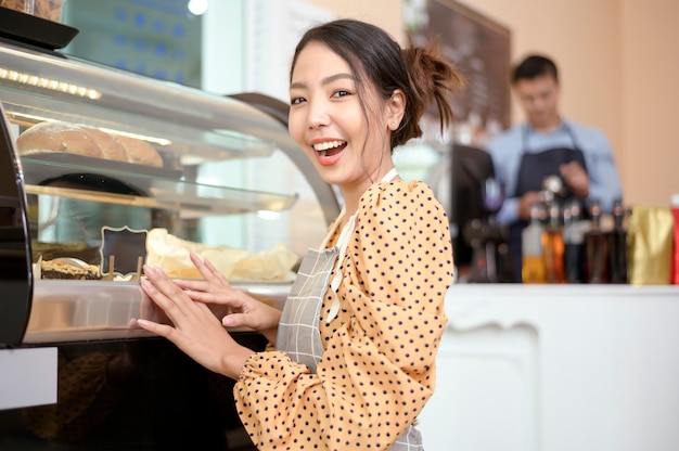 Una mujer hermosa panadería o dueño de una cafetería está sonriendo en su tienda