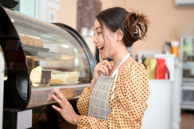 Una mujer hermosa panadería o dueño de una cafetería está sonriendo en su tienda