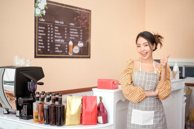 Una mujer hermosa panadería o dueño de una cafetería está sonriendo en su tienda