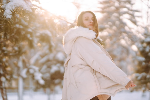 Mujer hermosa en un parque nevado Señorita caminando en un día soleado de invierno