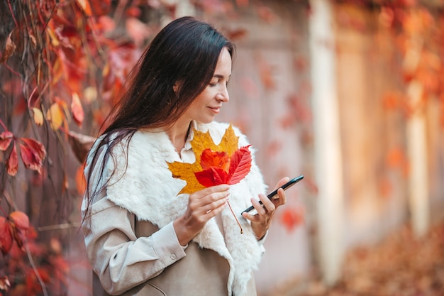 Mujer hermosa en el parque de otoño bajo el follaje de otoño