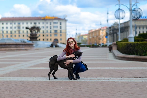 Mujer hermosa pelirroja paseando a su perro