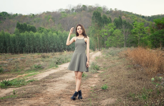 una mujer hermosa con el pelo largo con un vestido sentada en un prado y flores en la luz del atardecer.