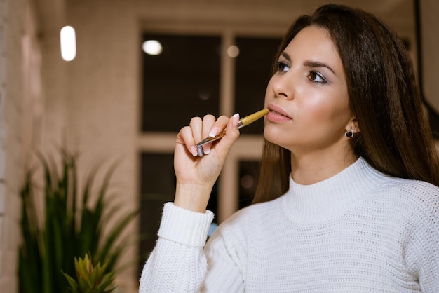 Mujer hermosa con una pluma en la mano pensativa