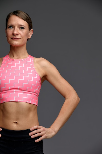 Mujer hermosa posando en el retrato de estudio de una joven morena feliz con una camiseta rosa para el yoga o el fitness.