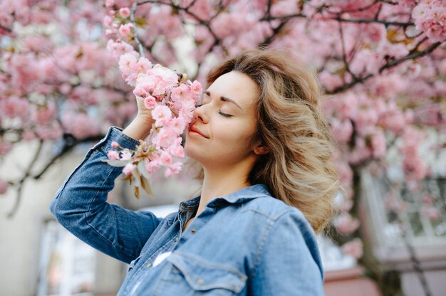 Mujer hermosa que disfruta del campo de la margarita, hembra agradable que se acuesta en el prado de flores, muchacha bonita que se relaja al aire libre, divirtiéndose, sosteniendo la planta, señora joven feliz y naturaleza verde de la primavera, concepto de la armonía