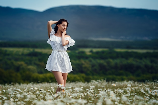 Mujer hermosa que disfruta del campo, muchacha bonita con el pelo oscuro que se relaja al aire libre, divirtiéndose, sosteniendo la planta, señora joven feliz y naturaleza verde de la primavera, concepto de la armonía