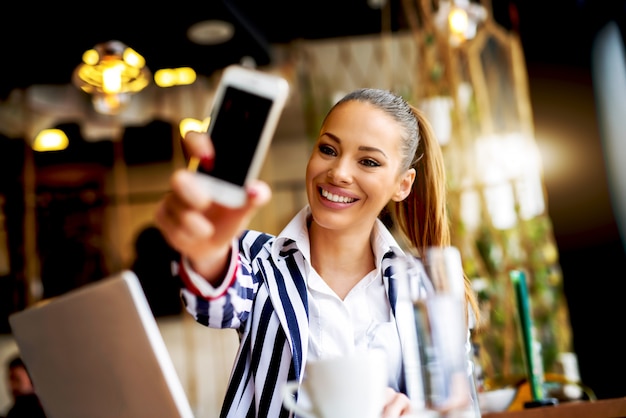 Mujer hermosa que hace el autorretrato en la cafetería.