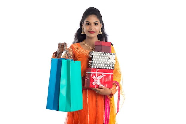 Mujer hermosa que lleva muchas bolsas de la compra y caja de regalo en blanco.