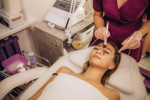 Foto mujer hermosa que recibe un procedimiento de microcorrientes faciales para levantar la cara rejuvenecimiento facial y estiramiento facial con terapia de microcorrentes foto de alta calidad