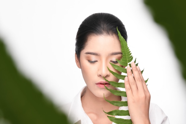 Mujer hermosa que sostiene la planta verde.