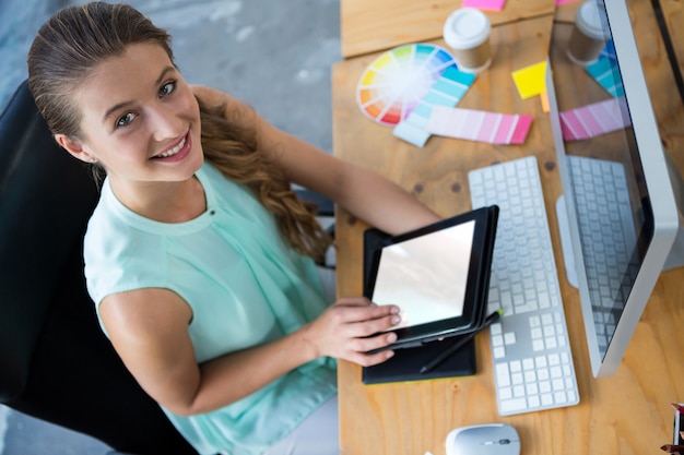 Foto mujer hermosa que sostiene la tableta digital en oficina