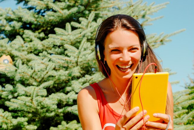 Mujer hermosa que usa la tableta al aire libre.