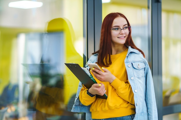 Mujer hermosa que usa el teléfono en el edificio de oficinas moderno