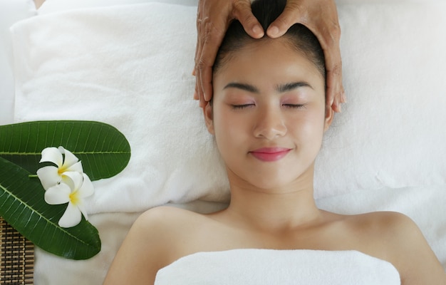 Mujer hermosa relajante que tiene un masaje para su piel en una cara en el salón de belleza