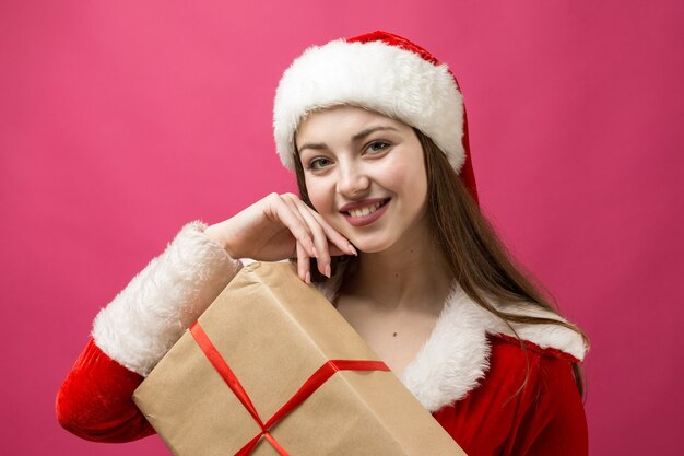 Mujer hermosa y sexy con traje de santa claus. La niña sostiene los regalos de Navidad.