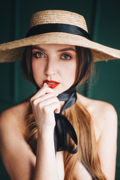 Mujer hermosa en un sombrero de paja con cintas negras.