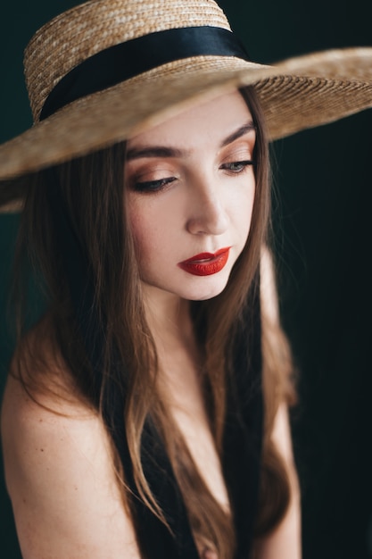 Mujer hermosa en un sombrero de paja con cintas negras.