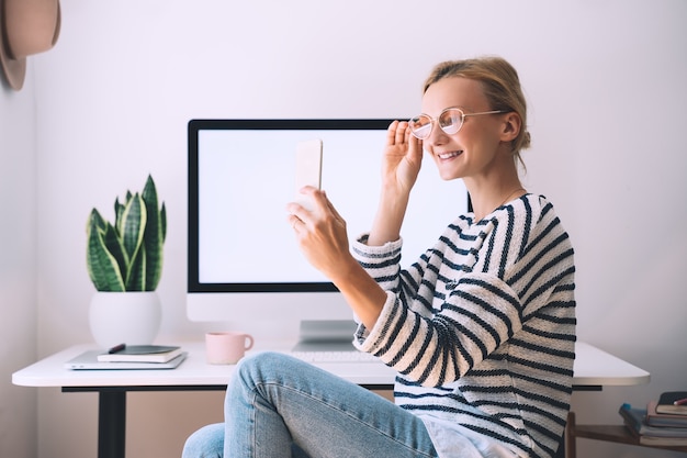 Mujer hermosa sonriente moderna que trabaja en la oficina en casa