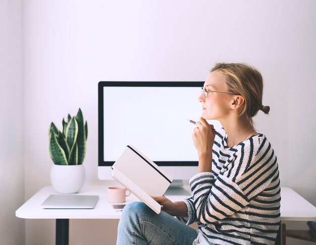 Mujer hermosa sonriente moderna que trabaja en la oficina en casa