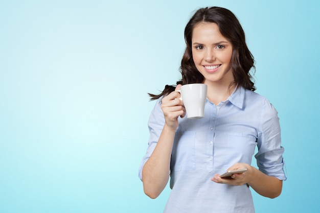 Mujer hermosa sonriente que manda un SMS con su teléfono