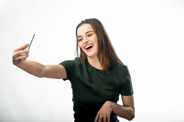 Mujer con una hermosa sonrisa hace un selfie en un estudio Fondo aislado Cerrar