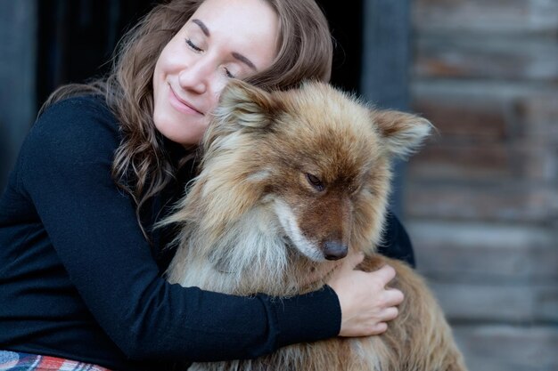 Una mujer hermosa y su perro pastor nenets laika sentados