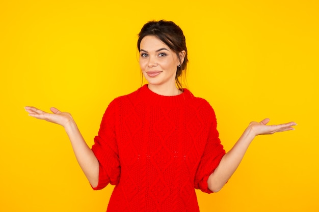 Mujer hermosa en el suéter rojo aislado en estudio amarillo.