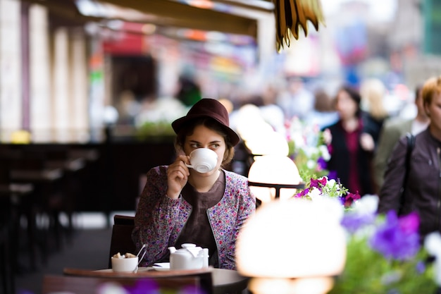 Mujer hermosa con una taza de té que se sienta en un café.