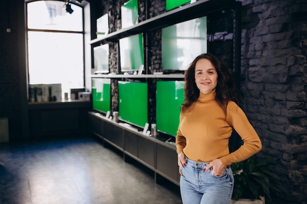 Una mujer hermosa en una tienda de tecnología elige un televisor