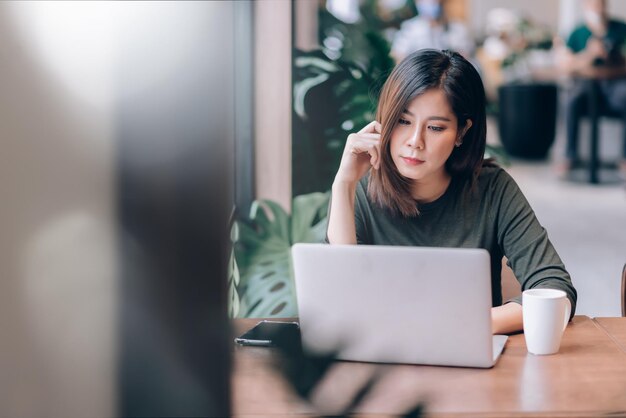 Mujer hermosa usando una computadora portátil mientras está sentada en una cafetería