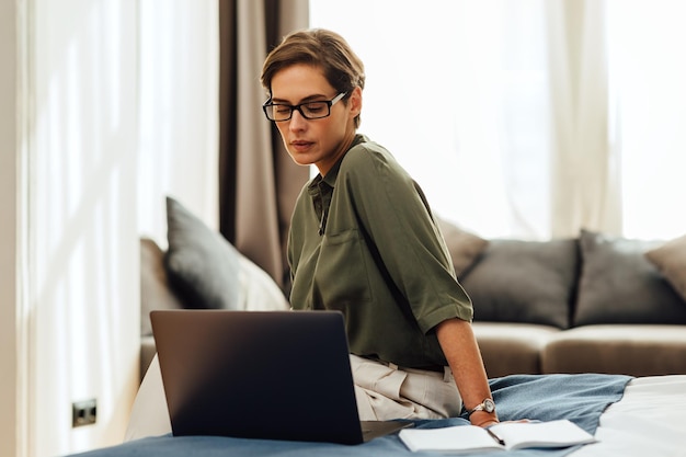 Mujer hermosa usando una computadora portátil sentada en casa