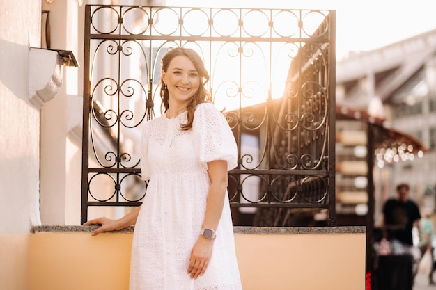 Una mujer hermosa con un vestido blanco al atardecer en la ciudad Fotografía callejera nocturna