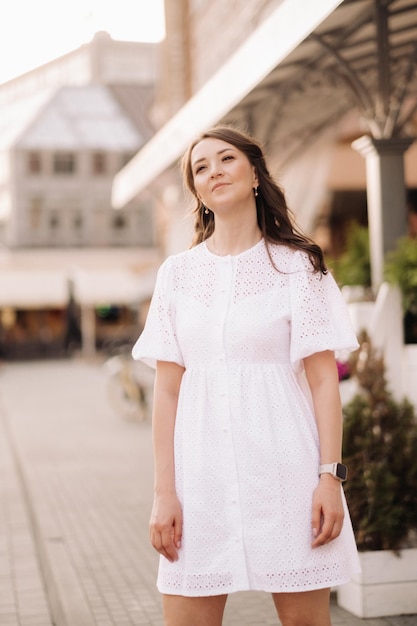 Una mujer hermosa con un vestido blanco al atardecer en la ciudad Fotografía callejera nocturna